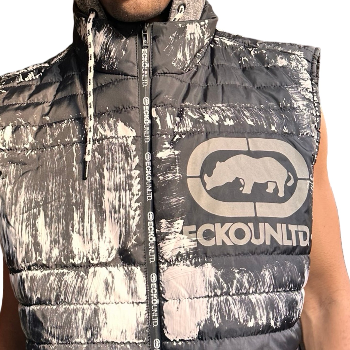 Close up of ASTROBOI* x Ecko Unltd black painted puffer vest with oversized gray hood, reflective logo, and white paint-stroke detailing. Custom streetwear made in NYC.
