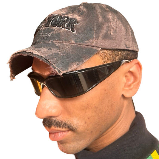 Front left of ASTROBOI* New York brown and black distressed half-visor hat with bold logo, black paint accents, and deconstructed grunge design. Handmade in NYC.